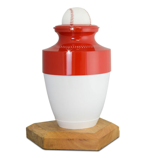 White baseball-shaped brass cremation urn with red stitching, set on a raised round base
