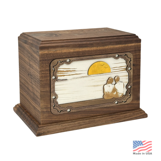Wood cremation urn carved with a layered sunset landscape scene across the front