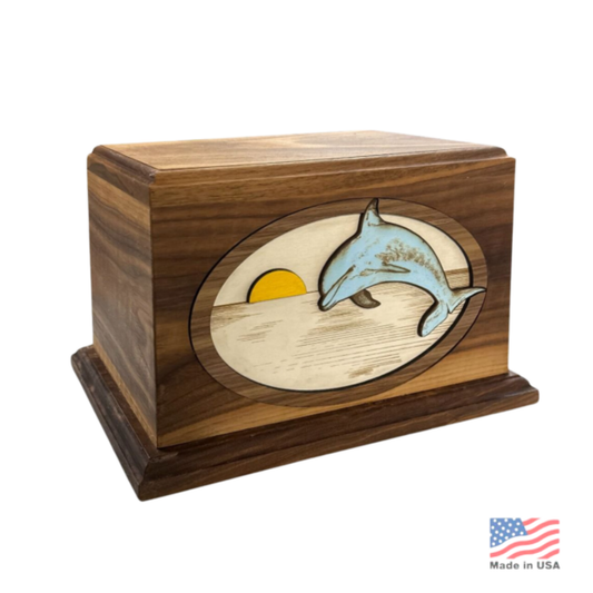 Wood cremation urn with a dolphin carved in high relief over a layered sunset and sea