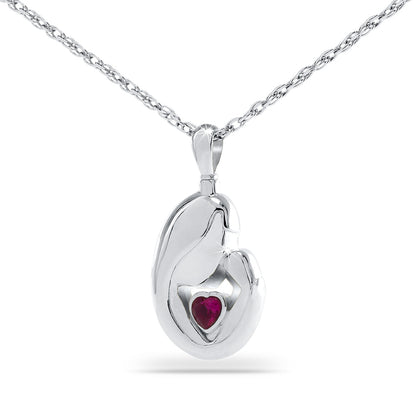 Silver pendant one inch tall with a red stone set at the front and a small side opening