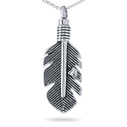 Wide stainless steel feather pendant lying almost horizontal with barbs cut into the metal
