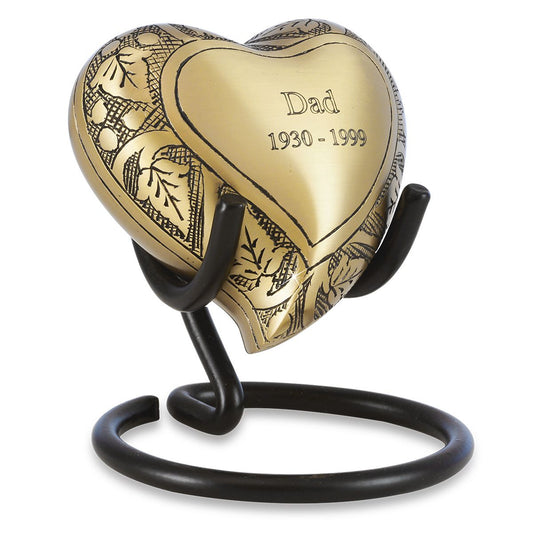 Brass heart-shaped keepsake urn with a raised vine and leaf pattern on the front