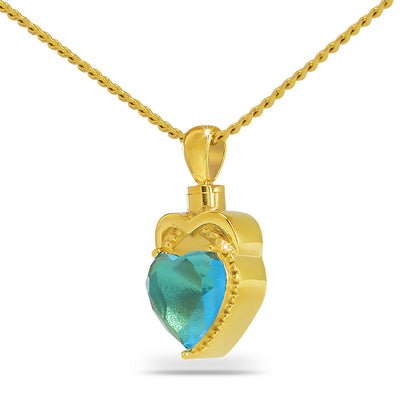 Gold-framed cremation pendant with a blue glass heart at its center